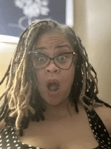 a woman with dreadlocks is wearing glasses and making a funny face