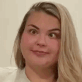 a woman with long blonde hair is making a funny face while wearing a white shirt .