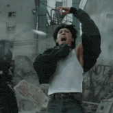 a man wearing a black jacket and a white tank top shouts