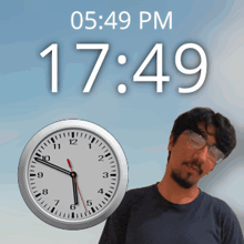 a man stands next to a clock that says 17:49