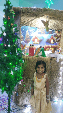 a little girl stands in front of a christmas tree