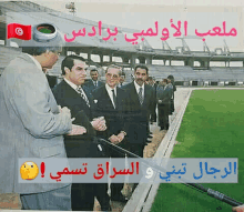 a group of men are standing in front of a stadium with arabic writing