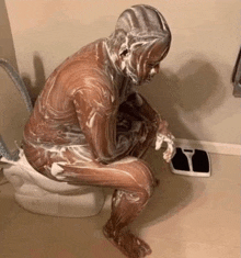 a man sitting on a toilet covered in shaving cream