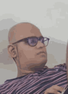 a bald man wearing glasses and a striped shirt .