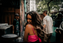 a woman in a pink top smiles while walking down a sidewalk