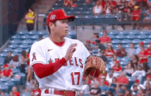 a baseball player in a red and white uniform is standing in front of a crowd in a stadium .