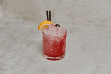 a red drink with a lemon slice and straws in it