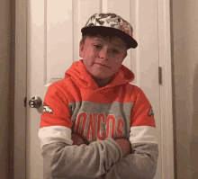 a boy wearing a denver broncos sweatshirt and hat