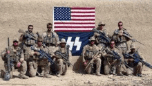 a group of soldiers are posing for a picture in front of a flag .