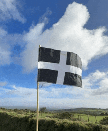 a black and white flag with a cross on it is waving in the wind