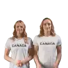 two women wearing white shirts that say canada are clapping