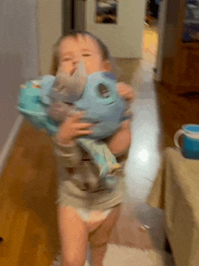 a baby in a diaper is holding a stuffed animal in his arms