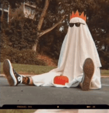 a ghost wearing sunglasses and a crown sits on the ground