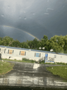 a double rainbow is visible over a mobile home in the rain