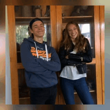 a boy and a girl are posing for a picture in front of a glass cabinet .