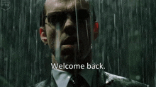 a man in a suit and tie is standing in the rain with the words welcome back on the bottom