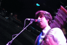 a man singing into a microphone with a purple background