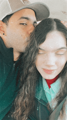 a man kissing a woman on the forehead with a hat that says abercrombie on it