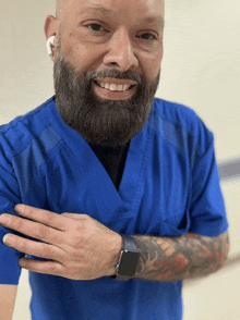 a man with a beard wearing a blue scrub top and a smart watch