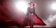 a woman in a superman costume is standing in a dark room .