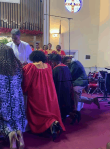 a group of people kneeling down in a church with a stained glass window behind them that says jesus on it