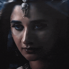 a close up of a woman 's face with a necklace on her forehead