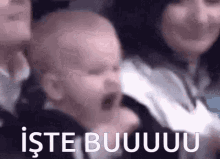 a baby is crying in front of a group of people with the words iste buuuu written on the bottom of the image .