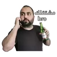 a man with a beard is talking on a cell phone while holding a bottle of beer that says bro