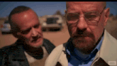 a man with glasses and a beard stands next to another man in a leather jacket .