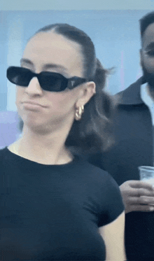 a woman wearing sunglasses and earrings is making a face