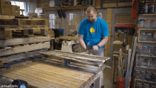 a man in a blue shirt is hammering a piece of wood in a workshop with jackman works written on the bottom