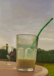 a glass of liquid with a green straw in it