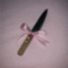 a knife with a pink bow around it on a pink surface