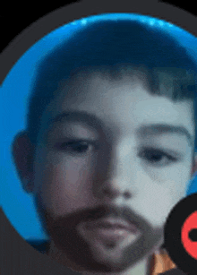 a young boy with a beard is looking at the camera with a blue background .