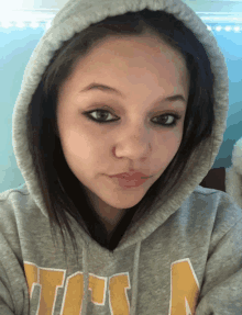 a girl wearing a grey hoodie with the word tors on the front