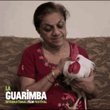 a woman is holding a white rooster in her arms and the words la guarimba international film festival are visible