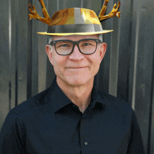 a man wearing a black shirt and a hat with antlers on it