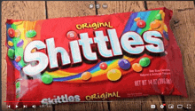 a bag of skittles sits on a wooden surface