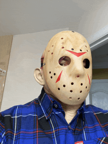 a man wearing a jason voorhees mask and a plaid shirt