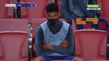 a man wearing a mask is sitting in a stadium watching a soccer match .