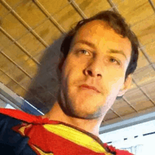 a man in a superman costume is making a funny face while looking at the camera .