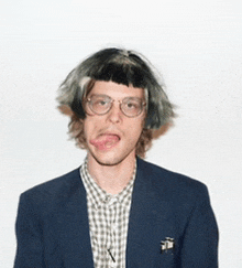 a man wearing glasses and a wig sticks out his tongue