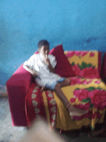 a boy is sitting on a couch with a blanket that says ' strawberry ' on it