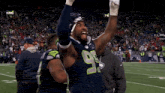 a football player with the number 99 on his jersey holds his arms in the air