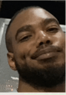 a close up of a man 's face with a beard smiling .