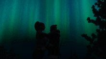 a silhouette of a man and a woman hugging in front of a green light