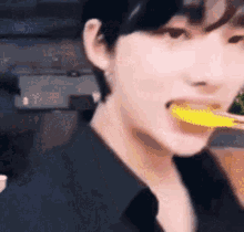 a close up of a person eating a yellow spoon .