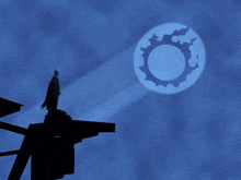 a statue of batman stands on top of a building with a full moon in the background