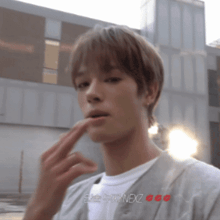 a man in a white shirt is holding his finger to his lips and the word nexz is on the bottom right