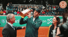 a man in a green jacket holds a trophy in front of a banner that says ' on ' on it